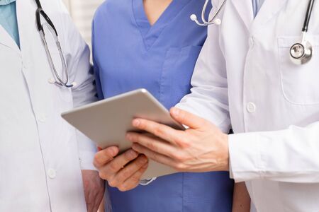 Doctor and surgeons standing and discussing reports or x-ray image with medical team of nurse and doctors about a patient at tablet computer in hospital. Technology in healthcare services.の写真素材
