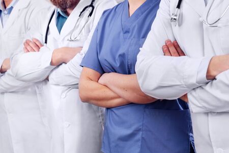 Doctors and surgeons in healthcare team with arms crossed in a row in hospitalの写真素材