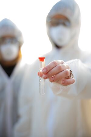 Female scientists holding water sample at beachの写真素材