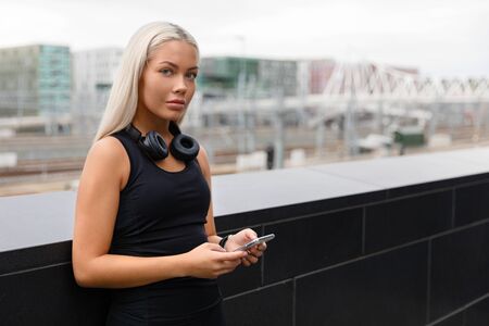Athletic Woman with Headphones and Smartwatch Rests After Workout In Cityの写真素材