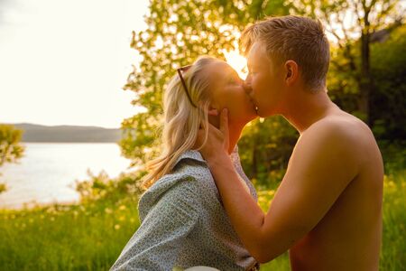 Young Shirtless Man Kissing Girlfriend During Sunsetの写真素材