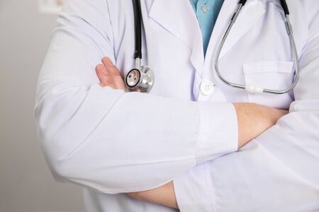 Midsection of mature male medical professional standing with arms crossed at clinic. Follow the professionals.の写真素材
