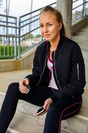 Sporty Woman Holding Protein Bar And Smart Phone On Stepsの写真素材