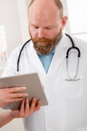 Doctors discussing report about a patient at tablet computer in hospitalの写真素材