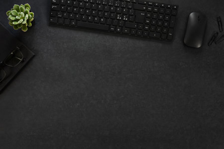 High angle view of black concrete office desk table with computer, supplies and green plant. Top...