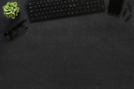 Top view of black concrete office desk with computer, phone and suppliesの写真素材