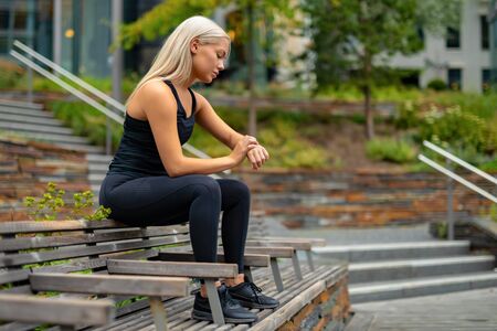 Fit woman setting up fitness smart watch device before runningの写真素材
