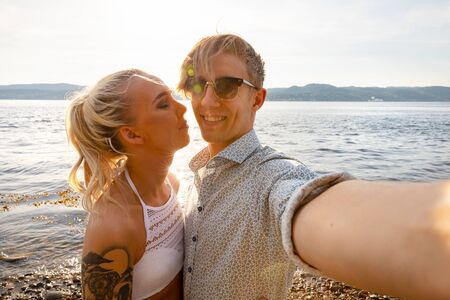 Happy Young Man Taking Selfie With Girlfriend At Beachの写真素材