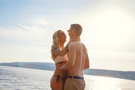 Happy laughing couple in love laughing at the beach against sunの写真素材