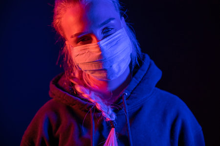 Exhausted or sick woman in protective face mask with multi colored lights