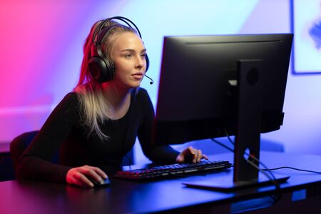 Professional E-sport Gamer Girl with Headset Playing Online Video Game on PCの写真素材
