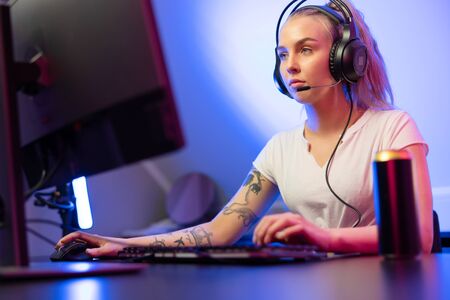 Professional gamer girl with headset play online multiplayer video game on PCの写真素材