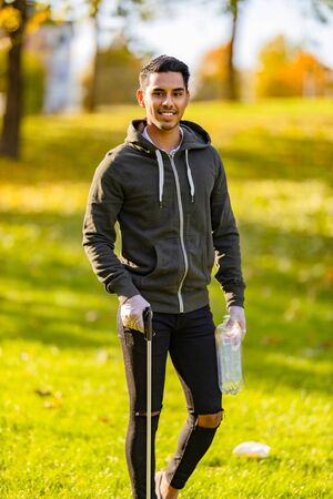 Confident volunteer cleaning park environment on sunny dayの写真素材