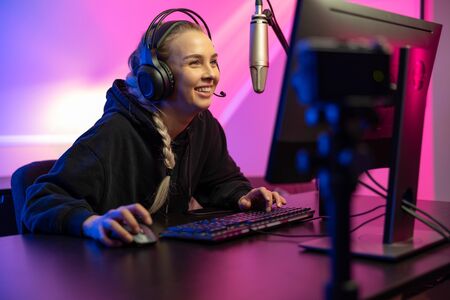 Professional smiling esport gamer girl live streaming and plays online video game on PCの写真素材