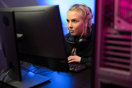 Focused Professional E-sport Gamer Girl with Headset Playing Online Video Game on PCの写真素材
