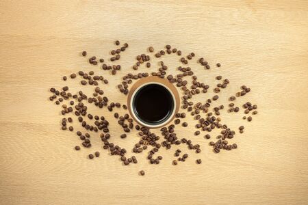 Overhead view of roasted beans and coffee in cup on tableの写真素材