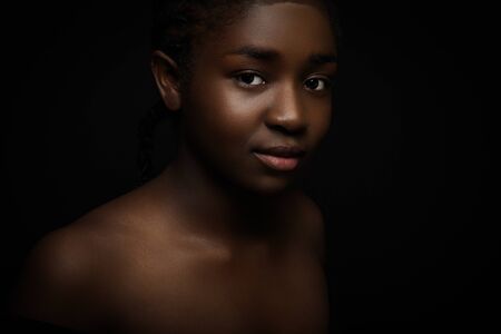 Natural and beautiful woman with dark skin on black bakgroundの写真素材