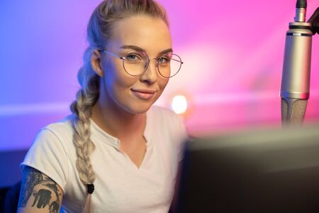 Portrait of Blonde Gamer Girl with Glasses Playing Online Video Game on Her Computerの写真素材