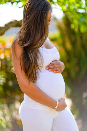 Close-up of pregnant woman standing outdoor holding hands on bellyの写真素材