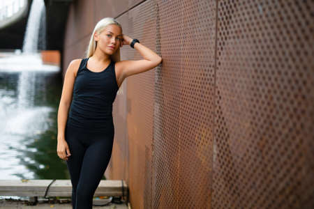 Beautiful Fit Woman in Sportswear Leaning On Metallic Wall After Workoutの写真素材