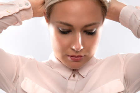 Beautiful female model in shirt holding her blonde hairの写真素材