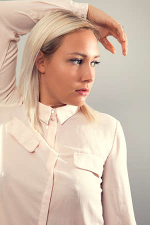 Pensive beautiful female blonde model in shirt looking away from cameraの写真素材