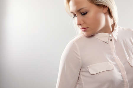 Pensive beautiful female blonde model in shirt looking away from cameraの写真素材