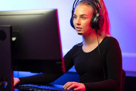 Professional E-sport Gamer Girl with Headset Playing Online Video Game on PCの写真素材