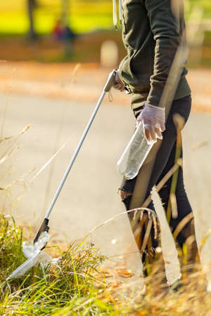 Male volunteer picking up plastic trash from grassの写真素材