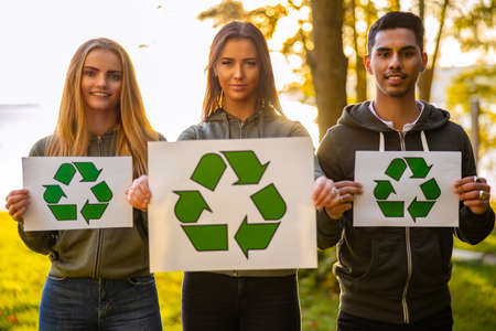 Young environment protective volunteers holding recycling symbol placardの写真素材