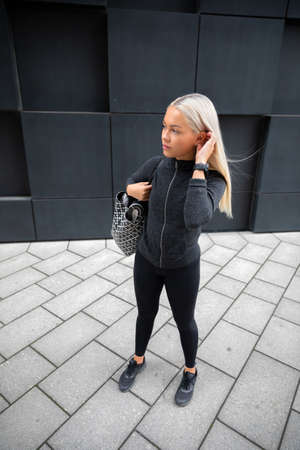 Beautiful sporty woman with bag goes to training in cityの写真素材