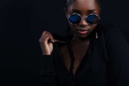 Confident and cool woman with dark skin wearing round sunglassesの写真素材