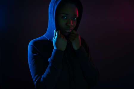 Dark colorful studio portrait of a cool black woman wearing hoodieの写真素材