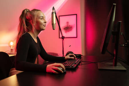 Happy and Beautiful Blonde Gamer Girl Playing Online Video Game on Her Personal Computer.の写真素材