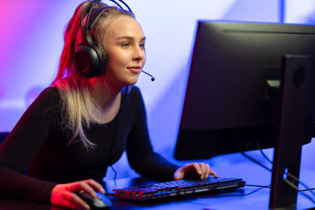 Focused E-sport Gamer Girl with Headset Playing Online Video Game on PCの写真素材