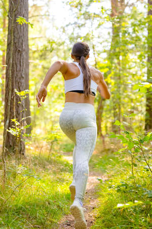 Female Running In Woodland During Outdoor Workoutの写真素材
