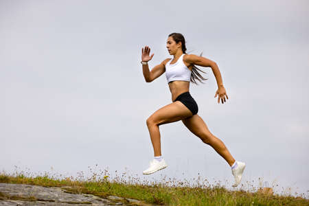 Determined Athlete Running On Mountain Against Skyの写真素材