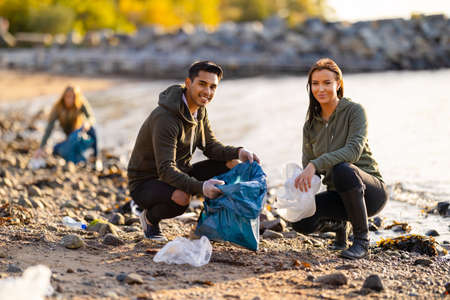 Portrait of smiling young volunteers cleaning beach for plasticの写真素材