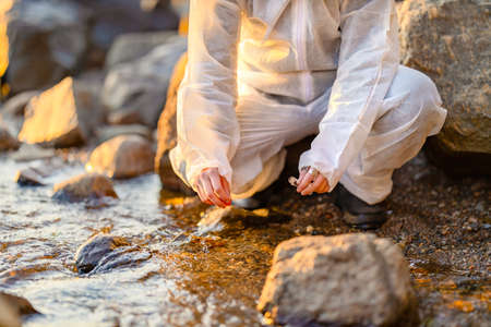 Close-up of researcher collecting water sample at seashoreの写真素材