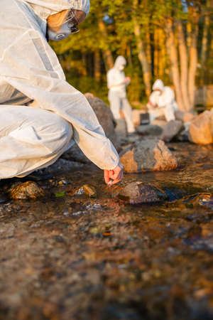 Female scientist in team collecting water sample from seaの写真素材