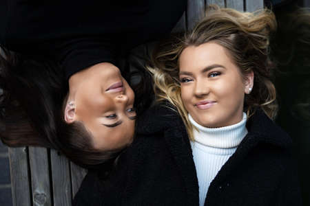 Portrait Of Two Smiling Best Friends Lying On Benchの写真素材