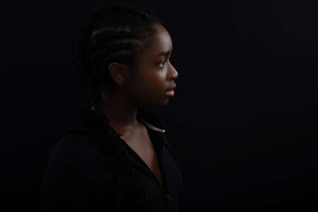 Natural and Beautiful Black Female Model Looking Away Against Black Backgroundの写真素材