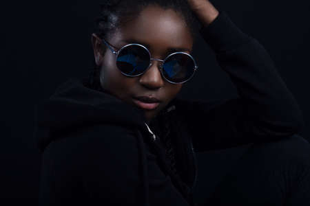 Close-up of cool woman with dark skin wearing round sunglassesの写真素材