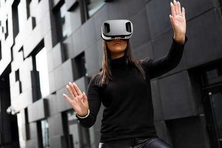 Female Using Virtual Reality Glasses And Wearing Black In Futuristic Cityの写真素材