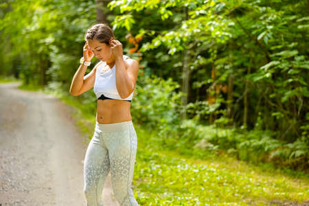Fit Woman Listening Music While Exercising Outdoorsの写真素材