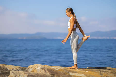 Slim Athletic Woman In Yoga Pose On Rockの写真素材