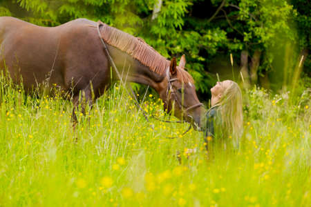 Smiling woman sitting in the meadow with her arabian horseの写真素材