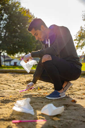 Back lit of male volunteer cleaning garbage on sand at parkの写真素材
