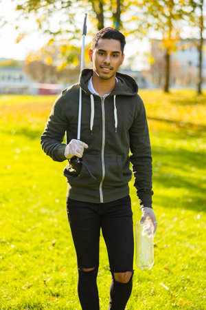 Confident and responsible volunteer cleaning park for trash on sunny day
