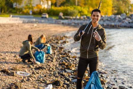 Proud man cleaning the ocean with volunteers on sunny dayの写真素材